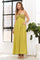 woman wearing a long yellow strapless maxi dress with a crochet bodice and pockets, standing in a bright room