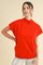 woman wearing a bright red short sleeve turtleneck sweater paired with shiny silver pants