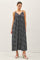 woman wearing a navy blue maxi dress with a patterned design and thin straps, standing against a plain background
