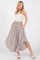 woman wearing a beige midi skirt with a smocked waistband and side pockets, paired with a white strapless top
