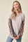woman wearing a beige ribbed long sleeve top with patterned sleeves and smiling