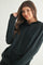 woman wearing a black long sleeve hooded top with buttons and drawstrings, smiling at the camera