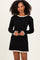 woman wearing a black ribbed long sleeve dress with ruffled cream trim on neckline and hem