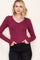woman wearing a burgundy long sleeve v-neck top with fitted style and ribbed texture