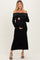 woman wearing a black off-the-shoulder maternity dress with studded details and holding her baby bump