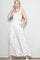 woman wearing a white maxi dress with a floral print, straps, and pockets, posing with one hand on her hip