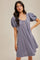 woman wearing a short lavender puff sleeve dress with a button detail and a relaxed fit