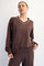 woman wearing a brown v-neck sweatshirt with white detailing and relaxed fit, posing against a white background