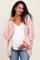 woman wearing a pale pink maternity hoodie over a white top and holding her baby bump while smiling