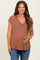 woman wearing a brown v-neck maternity top and holding her baby bump with a smile