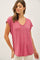 woman wearing a light pink short sleeve v-neck top with a relaxed fit and a slight hem detail