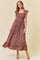 woman wearing a floral maxi dress with ruffled sleeves and a fitted bodice, standing against a neutral background