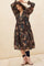 woman wearing a floral tiered midi dress with long sleeves and a deep v-neckline, paired with blush ankle boots
