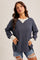 woman wearing a navy blue waffle knit long sleeve top with a white neckline and distressed denim shorts