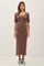 woman wearing a mauve ribbed midi dress with short sleeves and styling it with black and white sneakers