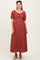 woman wearing a rust colored maternity maxi dress with puff sleeves and a gathered front, showcasing her baby bump