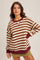 woman wearing a brown and cream striped oversized sweatshirt with maroon accents and a relaxed fit