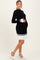 woman wearing a black and white ribbed maternity dress with a fitted bodice and flared hem, showing her baby bump