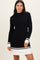 woman wearing a black ribbed knit dress with white pleated hem and striped sleeves