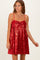 woman wearing a red sequin mini dress with a bow detail and spaghetti straps