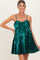 woman wearing a shiny teal maternity dress with a bow detail and a flared skirt, showcasing her baby bump