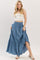 woman wearing a light blue maxi skirt with a tiered design and buttons, paired with a fitted white crop top