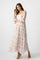 woman wearing a long sleeve floral maxi dress with a square neckline and flowy skirt standing against a plain background