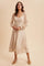 woman wearing a beige midi dress with lace long sleeves and a v-neckline, styled with subtle pleating at the bust