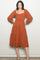 woman wearing a rust long sleeve polka dot midi dress with a square neckline and tiered skirt