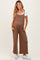 woman wearing a brown maternity jumpsuit with pockets and a white t-shirt underneath, displaying a baby bump