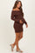 woman wearing a brown off-the-shoulder maternity sweater dress and holding her baby bump