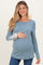 woman wearing a slate blue ribbed maternity top with lace details on sleeves and holding her baby bump