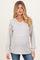 woman wearing a striped light gray and white maternity sweater with a v-neck and long sleeves, styled casually