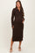 woman wearing a brown leopard print maternity dress with long sleeves and a side slit, holding her baby bump