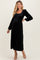 woman wearing a black smocked maternity dress with long sleeves and a fitted bodice, showcasing a baby bump