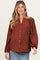woman wearing a brown polka dot maternity blouse with puff sleeves and a button-down front, showcasing her baby bump