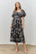woman wearing a black floral midi dress with puff sleeves and a gathered waist, standing in a modern setting