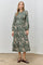 woman wearing a green floral midi dress with long sleeves and a tiered skirt, styled with brown shoes