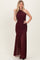 woman wearing a burgundy one-shoulder gown with ruching and a flowy skirt.