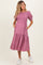 woman wearing a mauve maternity dress with puff sleeves, tiered skirt, and pockets, showcasing her baby bump