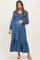woman wearing a blue denim maternity dress with long sleeves and a tiered skirt, gently cradling her baby bump