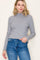 woman wearing a grey ribbed long sleeve turtleneck sweater with scalloped hem and paired with high-waisted jeans