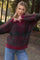 woman wearing a cozy burgundy and gray checkered maternity sweater with a v-neck, smiling outdoors in a forest setting