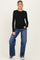 woman wearing a black long sleeve maternity top and blue wide-leg jeans with a visible baby bump