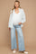 woman wearing a white maternity tank top, striped shirt, and light blue flared jeans, showcasing her baby bump