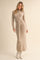 woman wearing a beige ribbed knit long sleeve maxi dress with a tied waist detail and white ankle boots