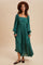 woman wearing a teal long sleeve maxi dress with a square neckline, puff sleeves, and a tiered skirt, styled with a brown hat