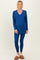 woman wearing a blue maternity loungewear set with a v-neck long sleeve top and matching leggings, showing a baby bump