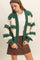 woman wearing a green and cream oversized knitted cardigan over a white top and a brown button-up mini skirt