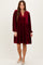 woman wearing a burgundy velvet long sleeve dress with a v-neck and button detailing